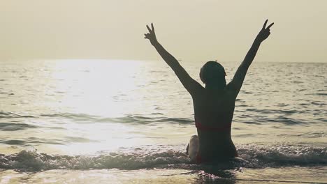 girl silhouette shows victory gesture at ocean slow motion