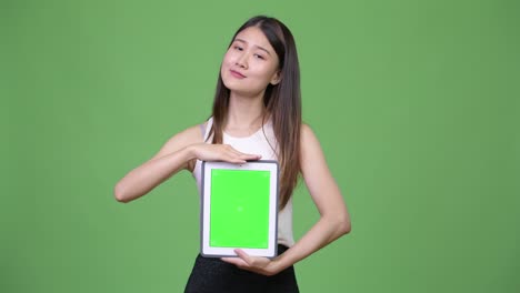 젊은 아름다운 아시아 사업가 여성이 디지털 태블릿을 보여줍니다.