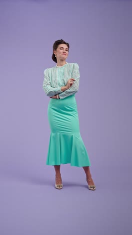 elegant woman in vintage style teal skirt and polka dot blouse on purple background