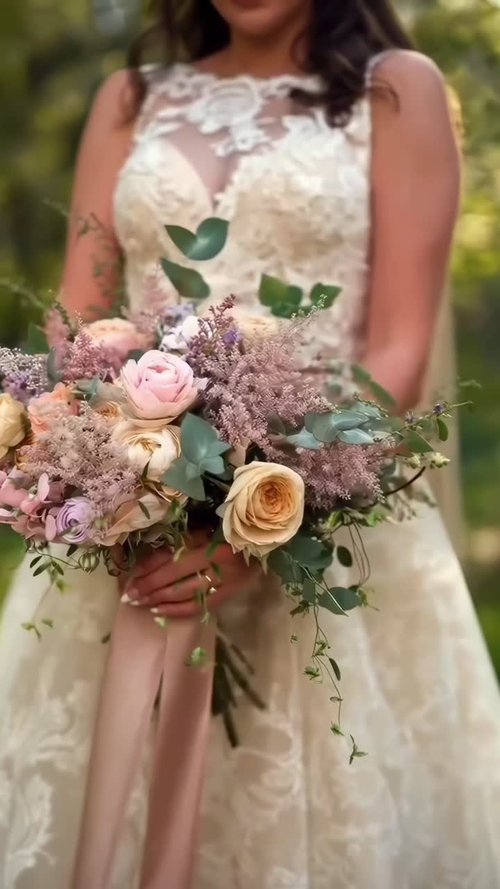 Angolazione video ravvicinata di una sposa che tiene un bouquet floreale dai colori pastello, che mette in mostra l'eleganza