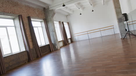 empty dance and fitness studio with wooden floor and large windows