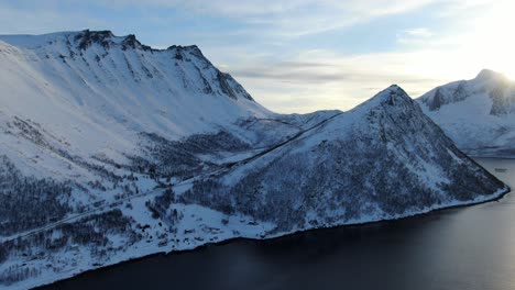 Drone-view-on-the-Tromso-mountains-in-winter-full-of-snow-showing-norwegian-mountains-next-to-the-sea-in-Norway