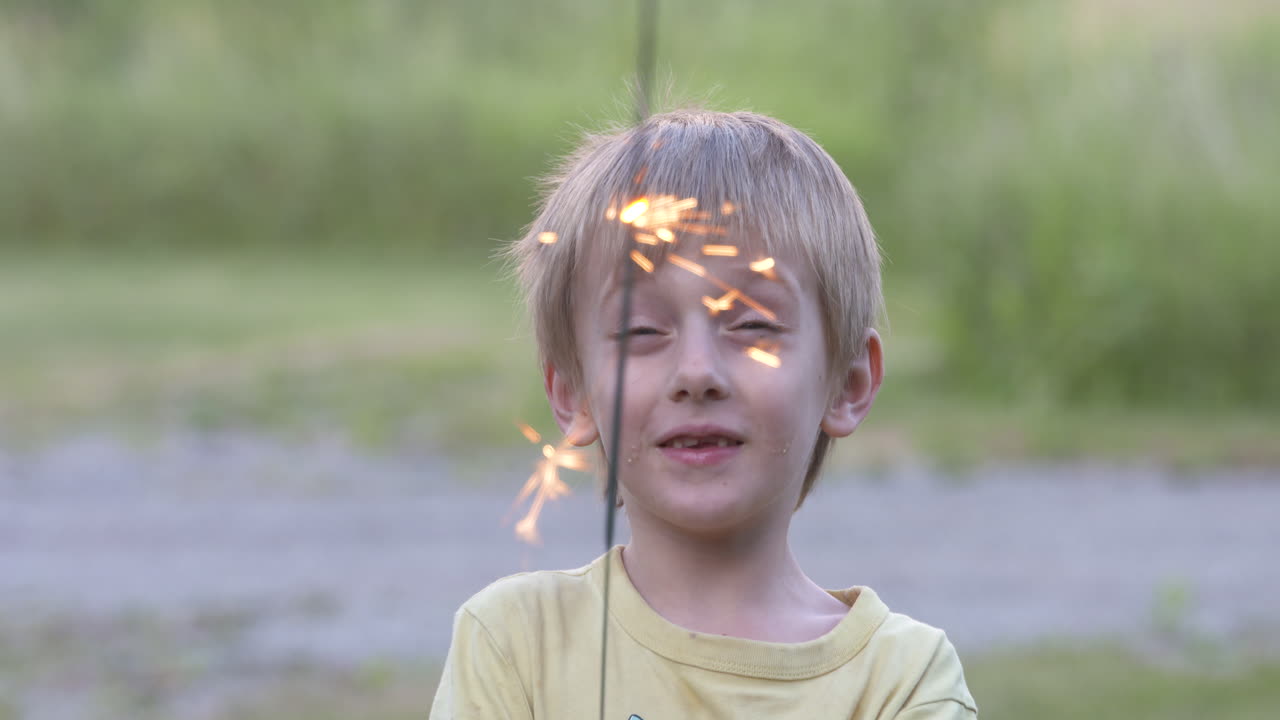 niño feliz jugando con una bengala en una tarde de verano
