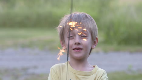 happy little boy playing with a sparkler on a summer evening