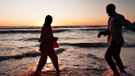 couple, playful splash and beach in sunset