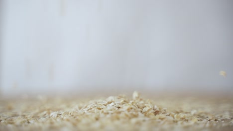 oat flakes fall in pile in slow motion, close up with copy space, side view