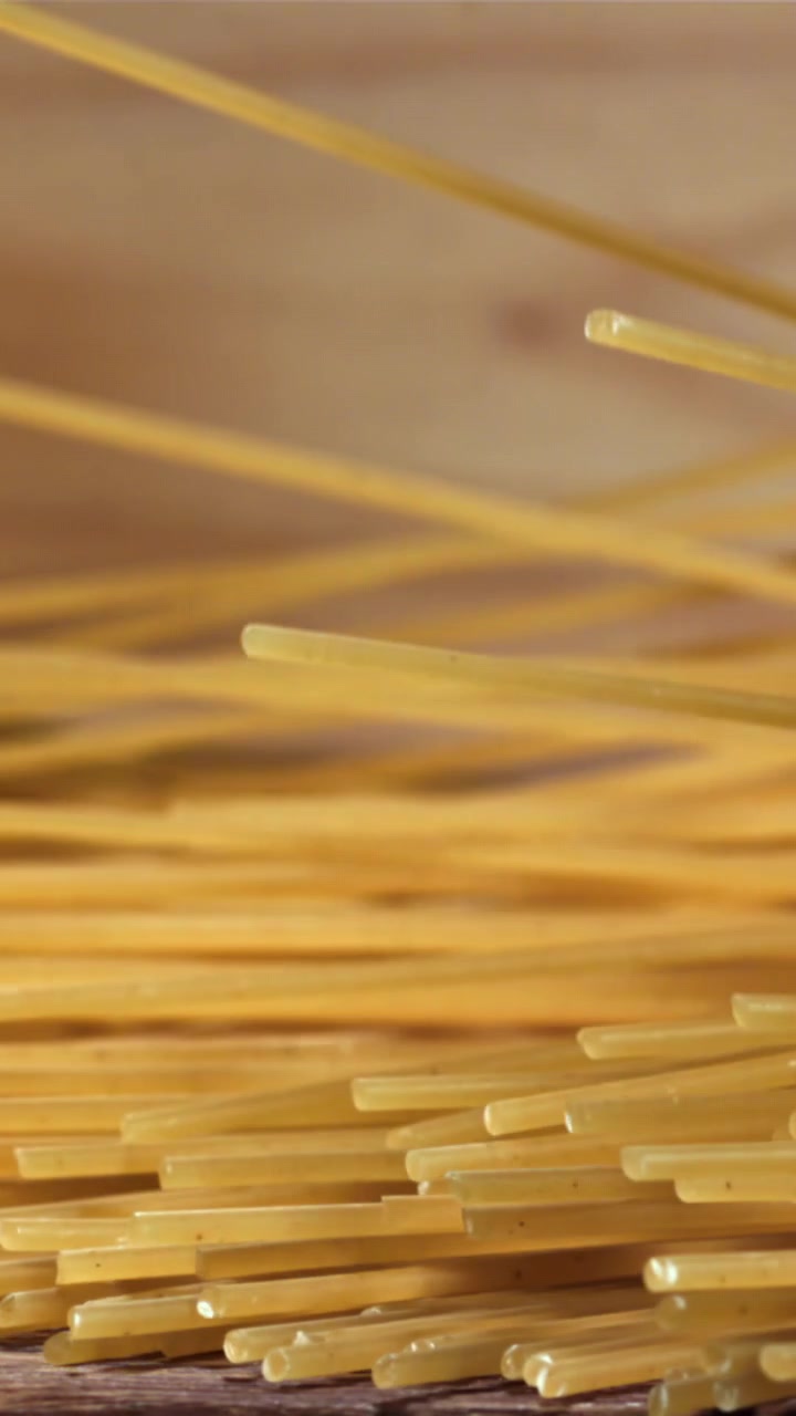 Movimento rallentato di spaghetti crudi che cadono su un piano di legno