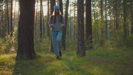 joven con uñas largas caminando por un bosque exuberante, caminando con confianza entre los árboles mientras la suave luz del sol de la tarde se filtra a través de las ramas, rodeada de árboles altos y vegetación fresca