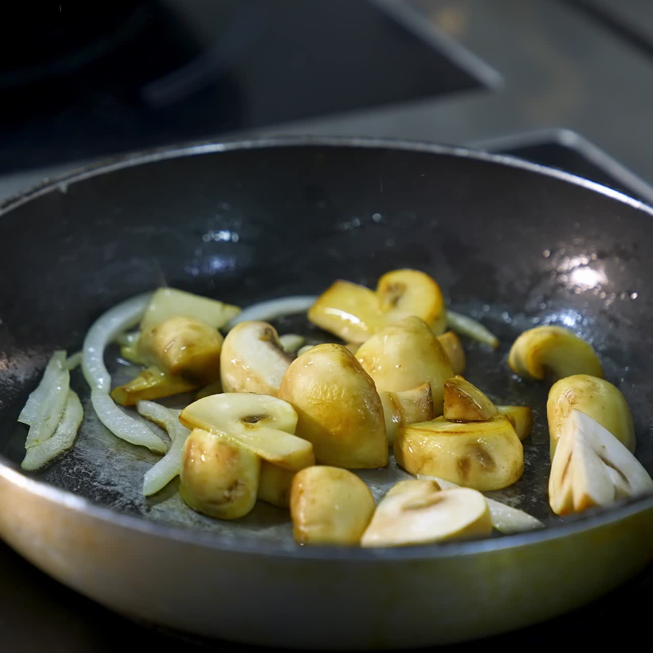 Cottura di funghi in padella. Deliziosi funghi friggono con cipolle nell'olio su un fornello. Primo piano