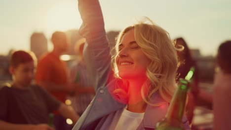 cheerful girl dancing with beer bottle at party. partying people hanging out.