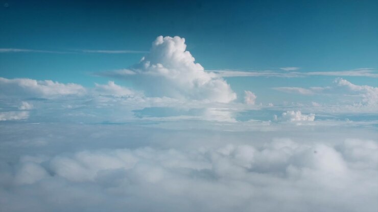 Cumulus nimbus clouds with a dreamy blue sky as seen from the window of a plane
