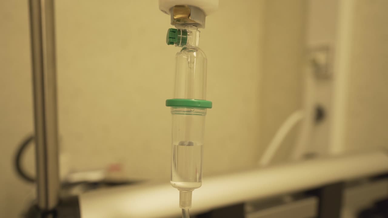 крупный план медицинского пластикового набора для выдачи прозрачного резервуара, наполненного внутривенной жидкостью и медленными капельницами для лечения пациента в больнице во время пандемии коронавируса