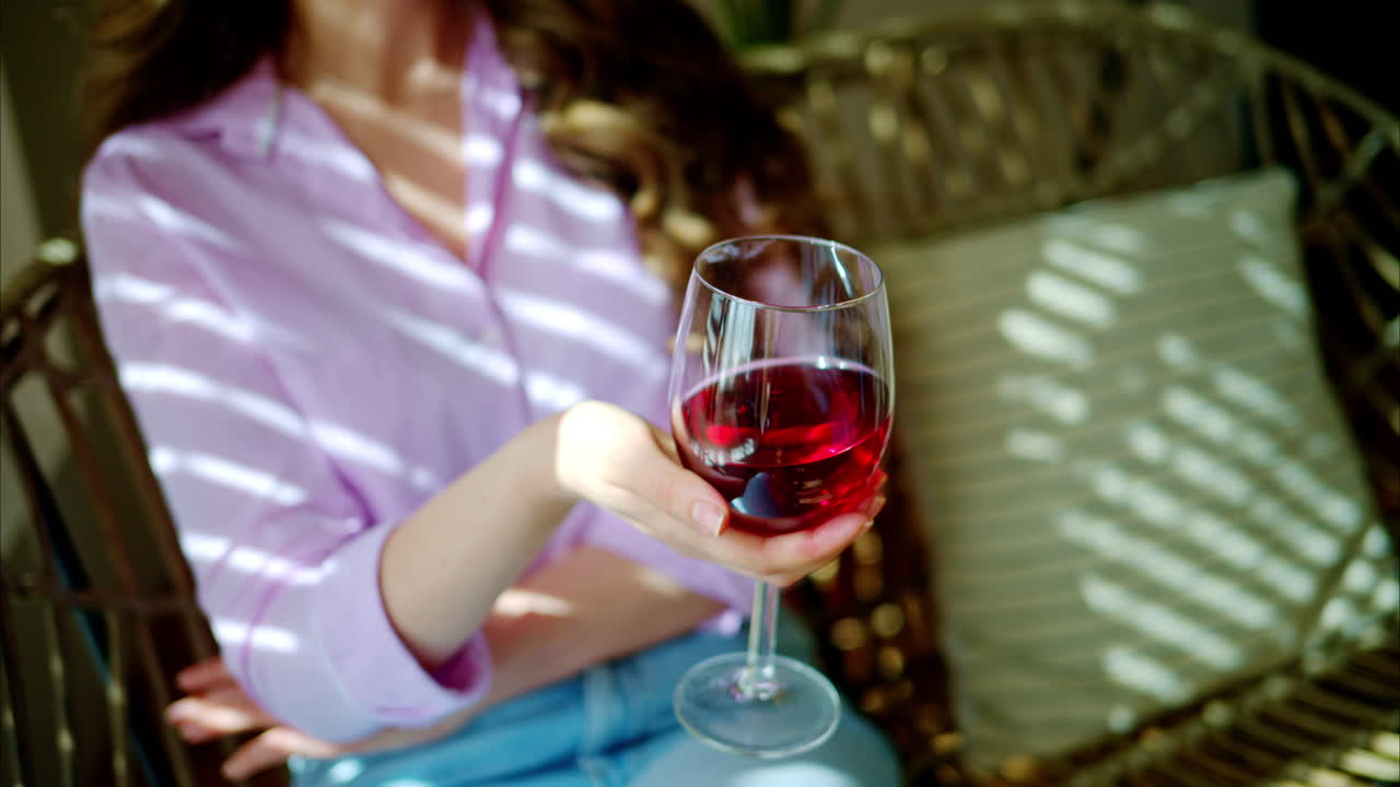 Woman swirling a glass of red wine in daylight