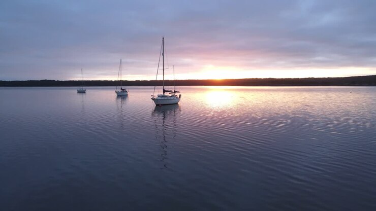 yates de vela flotando en el puerto deportivo mientras los drones giran alrededor de los barcos