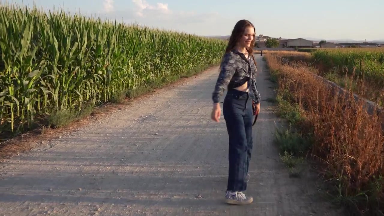Una ragazza si gode una passeggiata su un sentiero pittoresco, circondata da splendidi campi e dalla natura.