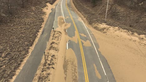 Avance-A-Lo-Largo-De-Una-Carretera-Acondicionada-Para-El-Invierno-Cubierta-De-Arena-Por-Los-Fuertes-Vientos