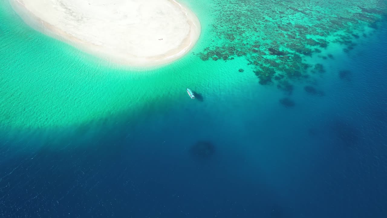 un avión no tripulado se acerca a un barco solitario amarrado en un pequeño islote en la unión de las comoras, el parque nacional marino de la isla moheli