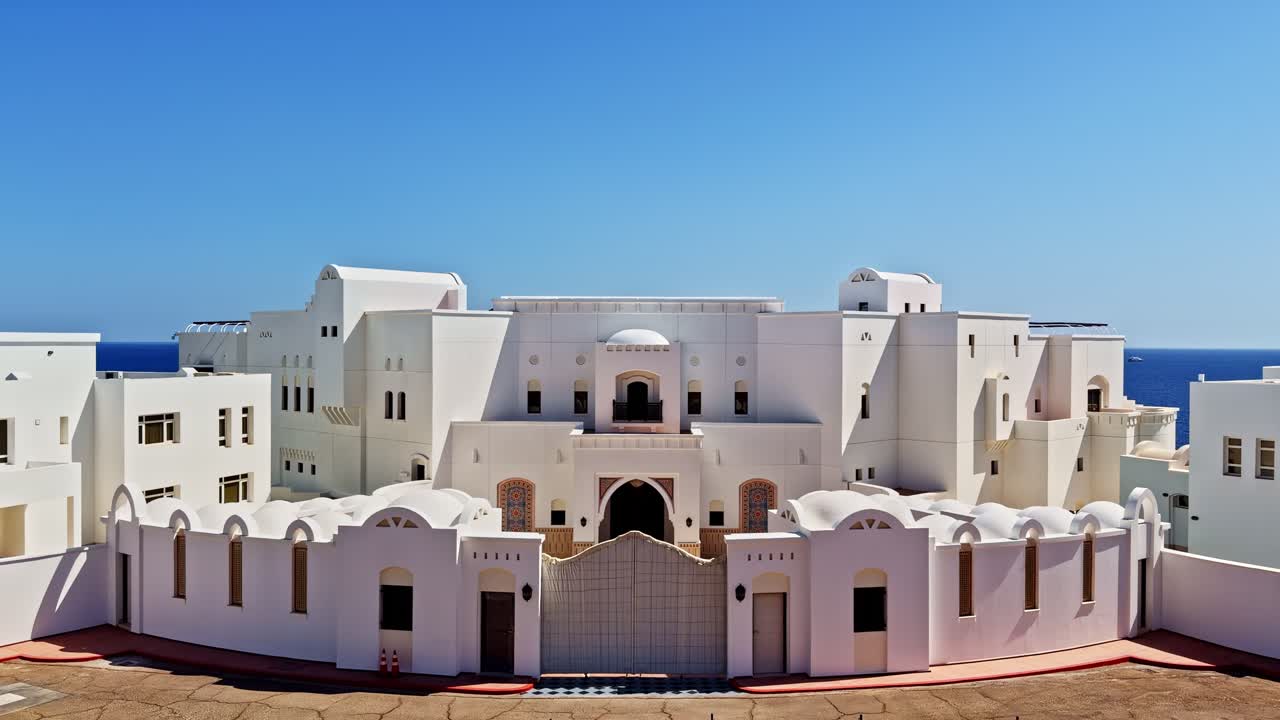 White resort buildings with domed roofs under bright blue sky, Egyptian architecture overlooking ocean