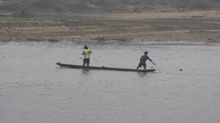 Two men in a dugout canoe fishing on a river in the Chitwan National Park in Nepal