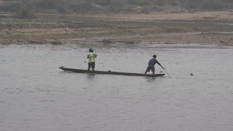 Two-men-in-a-dugout-canoe-fishing-on-a-river-in-the-Chitwan-National-Park-in-Nepal