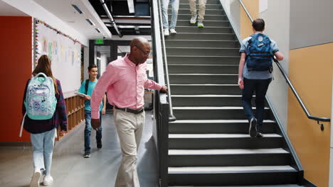 estudiantes de secundaria y el maestro caminando por las escaleras en el edificio de la universidad ocupado