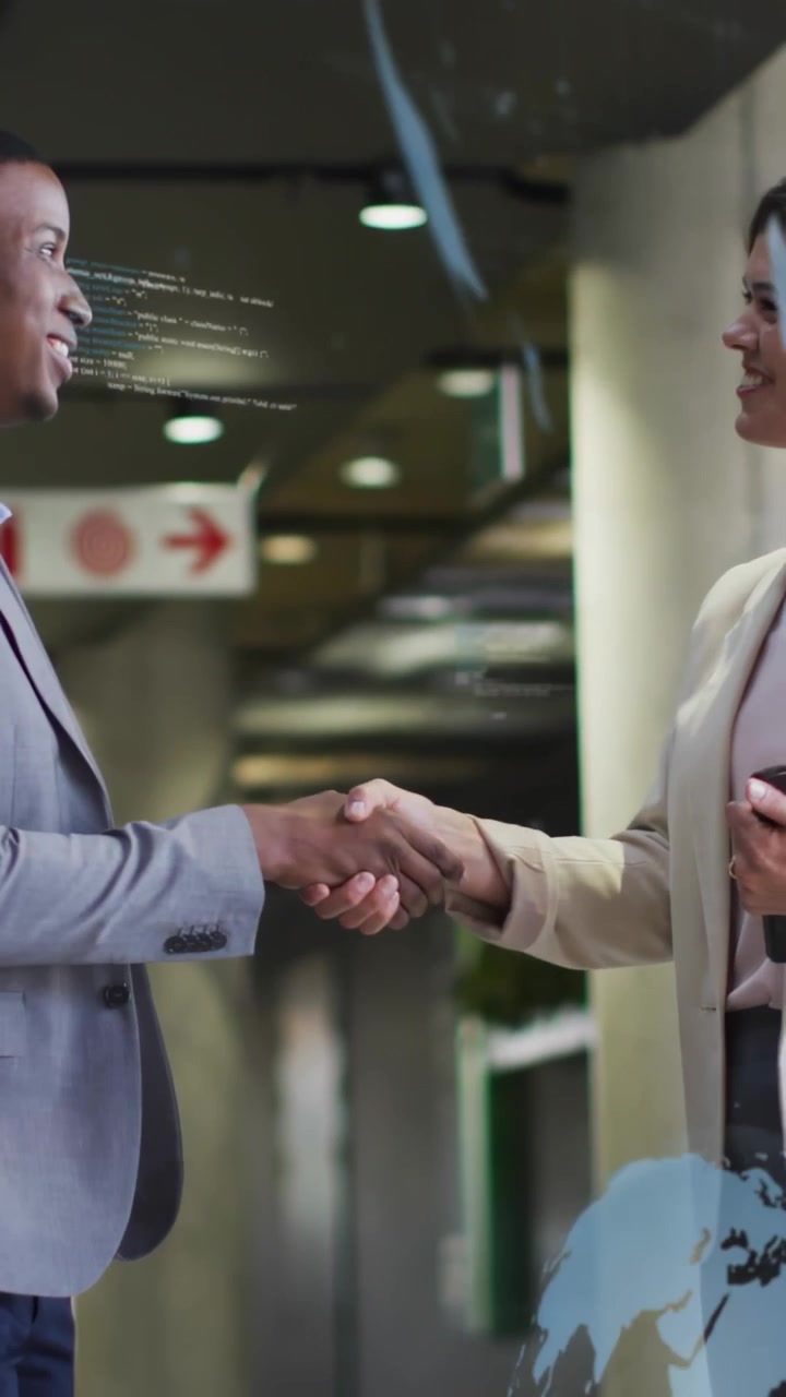 Vertical video: Man and woman shaking hands in business lobby, sparking globe chart, sealing deal