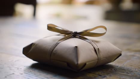 a beautifully wrapped package with a delicate bow on a rustic wooden table, evoking a sense of surprise and anticipation for what's inside