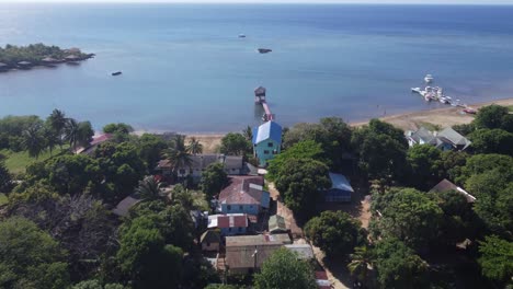 Flyover-to-Caribbean-sea-on-quiet-afternoon-at-Camp-Bay,-Roatan-HND