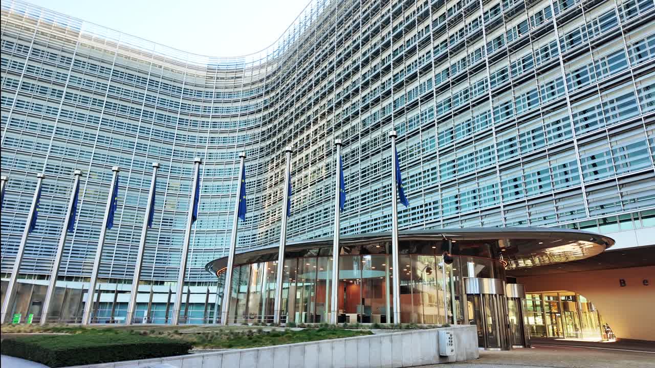European Union flags in a row waving in the wind in front of European Commission, Berlaymont building