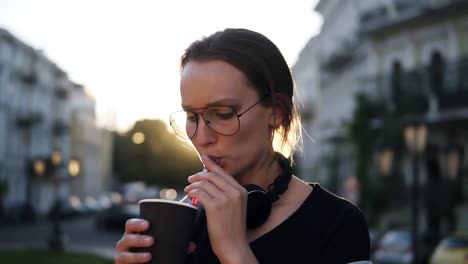 Junge-Frau-In-Stylischer-Sonnenbrille,-Die-Auf-Der-Straße-Einen-Kaffee-Mit-Plastikstrohhalmen-Trinkt