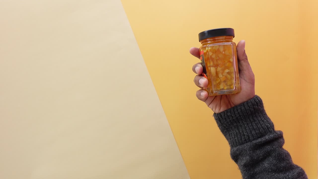 Hand holding a jar of orange marmalade