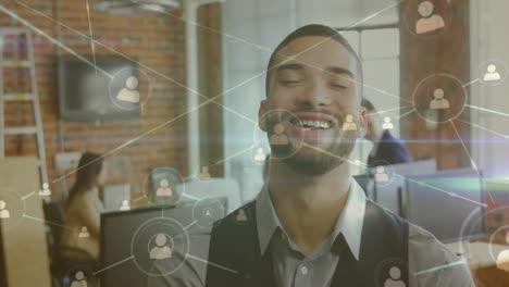 animation of network of people icons over happy biracial casual businessman laughing at office