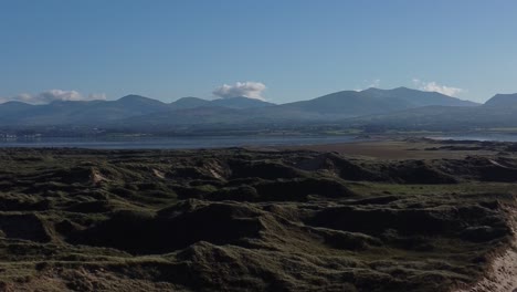 estableciendo una vista aérea sobre la costa de las dunas de arena de la playa de newborough y el horizonte nebuloso de la cordillera de snowdonia