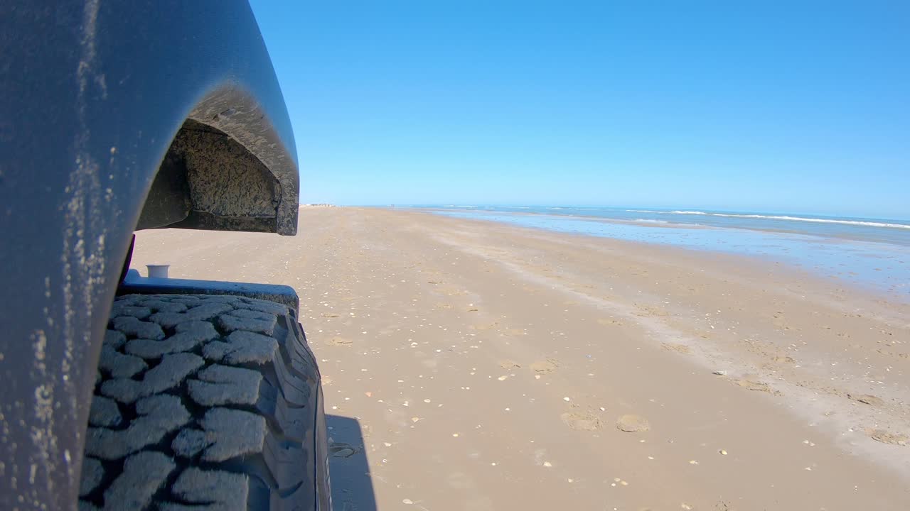 사우스 파드레 섬 텍사스의 화창한 날 모래 위를 운전하는 차량의 오른쪽 앞 타이어와 해변 서핑 - 관점, pov