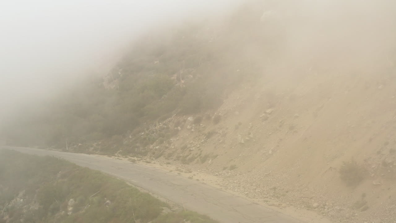 버려진 아스팔트 산길 위로 뒤로 날아가는 드론