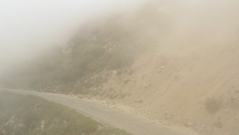 drone volando hacia atrás sobre una carretera de montaña de asfalto abandonada