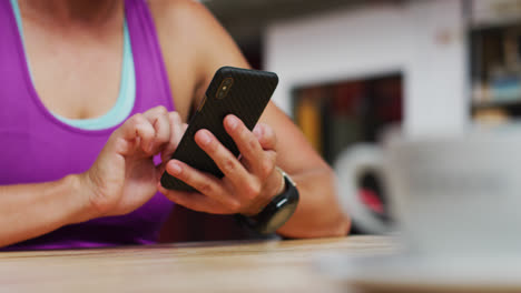 Mittelteil-Einer-Kaukasischen-Frau,-Die-Ihr-Smartphone-Im-Café-Im-Fitnessstudio-Benutzt