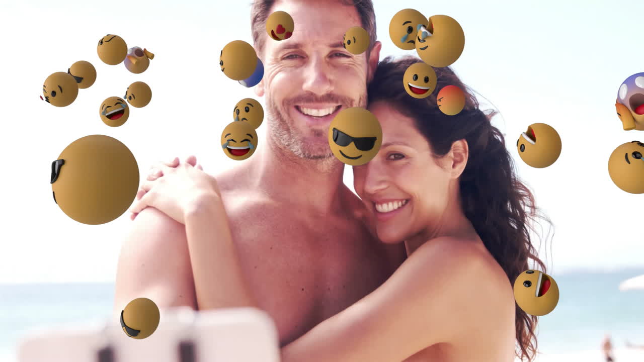 Smiling couple embracing at beach with floating emoji animations around them