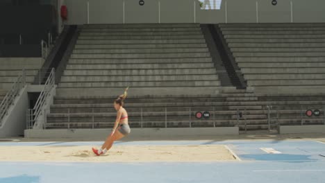 side view of caucasian athlete doing long jump