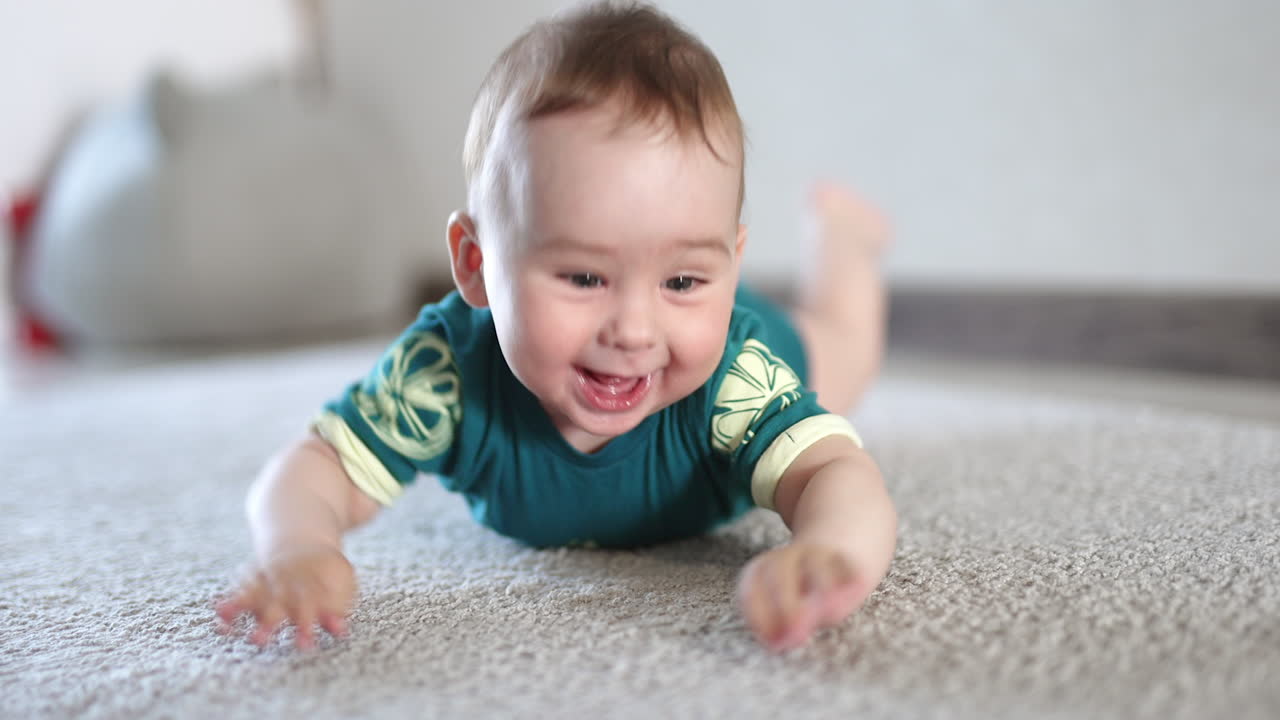 Happy beautiful boy clapping hands over the floor. Smiling child being active. Close up. Blurred backdrop.