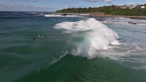 surfer disappearing in a big wave during golden hour