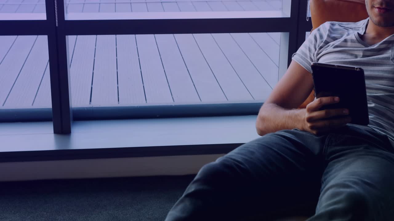 자리에 앉은 남자가 태블릿을 켜서 홀로그램 금융 차트를 스크롤하며 시장 동향을 검토하고 있어요