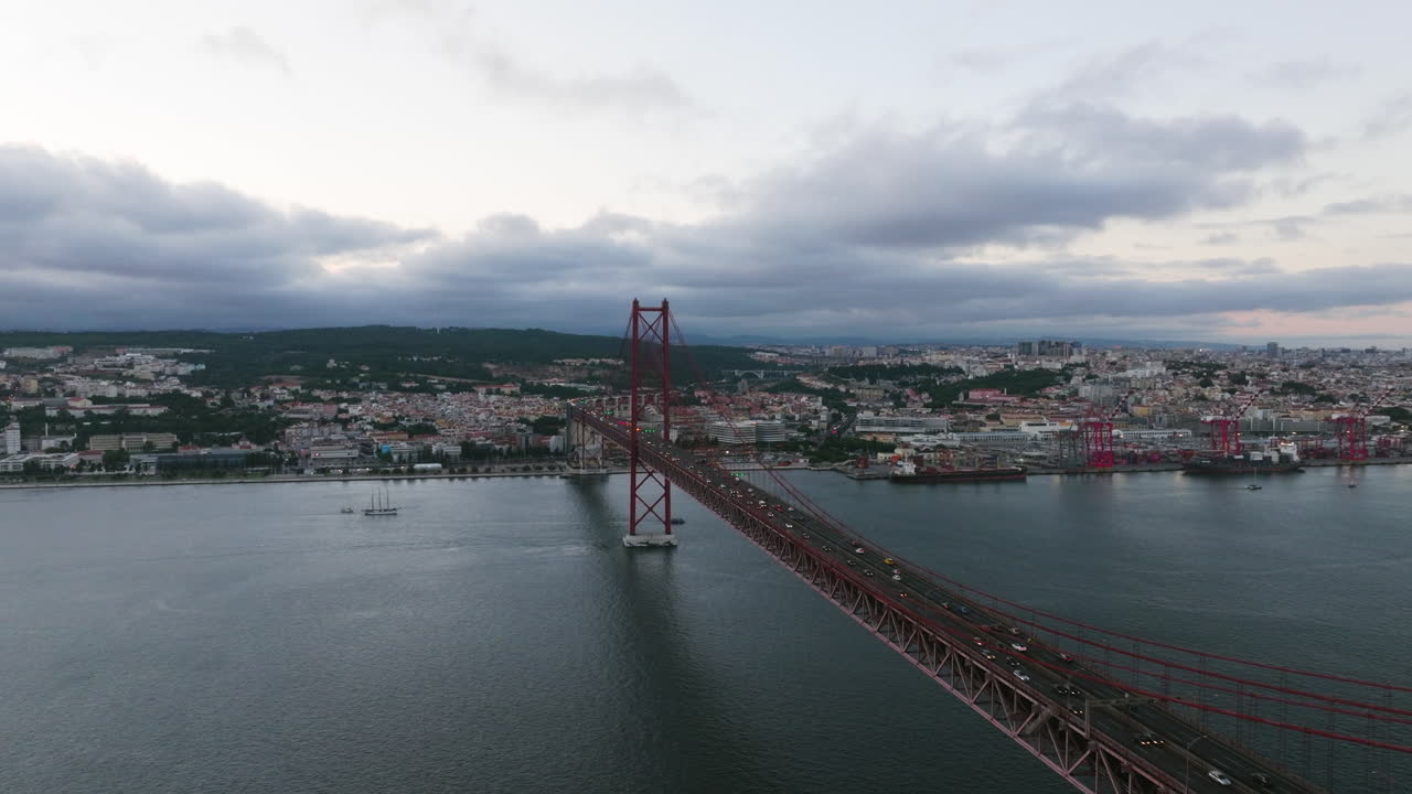 Aerial view along the Ponte 25 Abril bridge on Tagus river, cloudy dusk in Lisbon