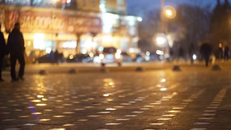 bokeh cinematográfico con la calle de la ciudad de la noche y la gente a la luz de los faros y linternas