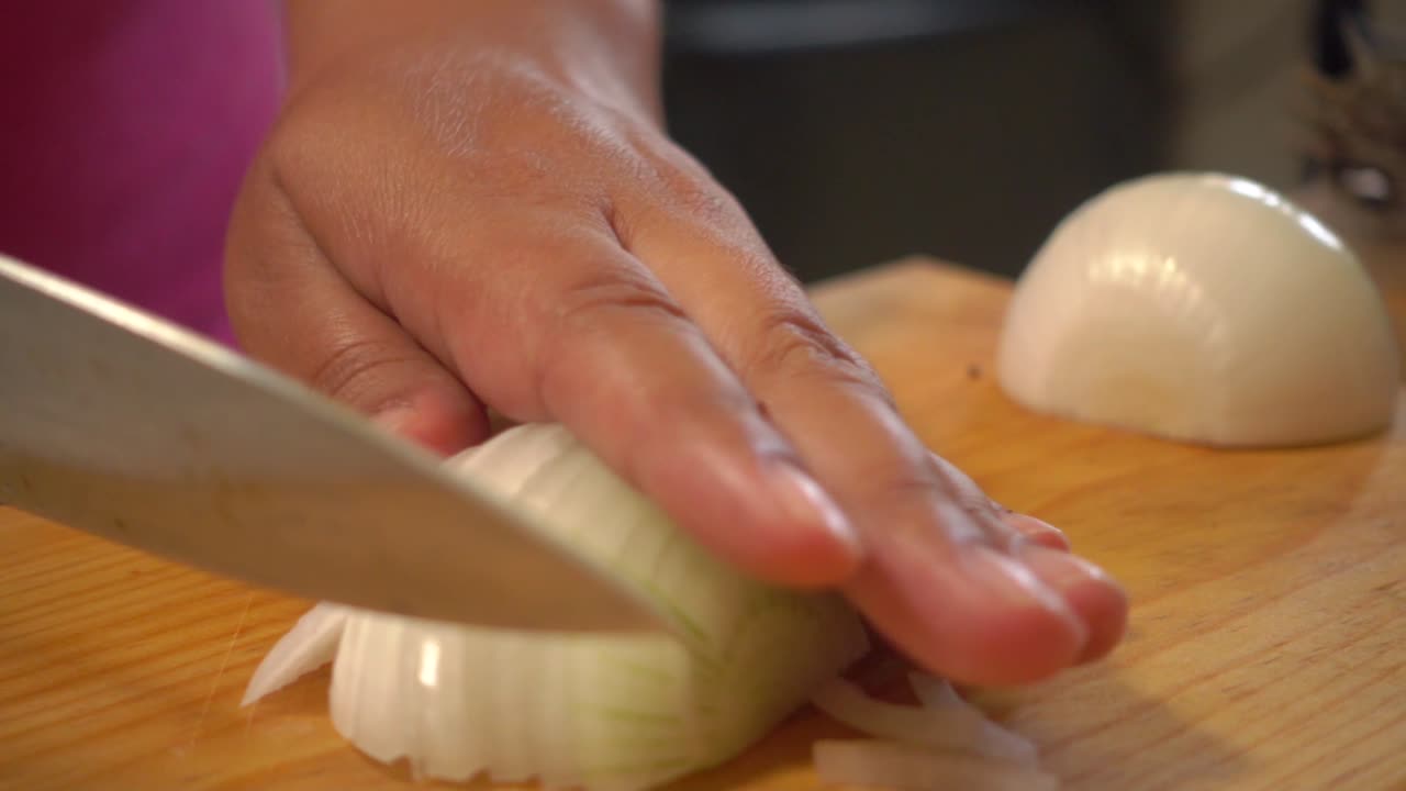 Hands slicing and cutting a yellow onion