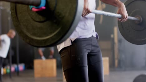 Focused-biracial-man-lifting-barbell,-free-weight-training-at-gym,-in-slow-motion