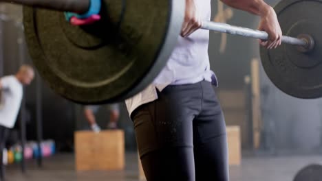 집중된 두 인종의 남자가 바벨을 들어 올리고, 체육관에서 자유로운 웨이트 트레이닝을 하고, 느린 동작으로