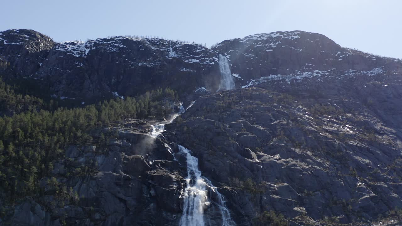 Majestic Norwegian forest mountain waterfall landscape upward looking to sky dolly right