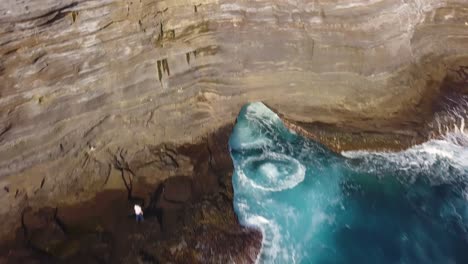 man jumps off of spitting cave revealing beautiful blue water