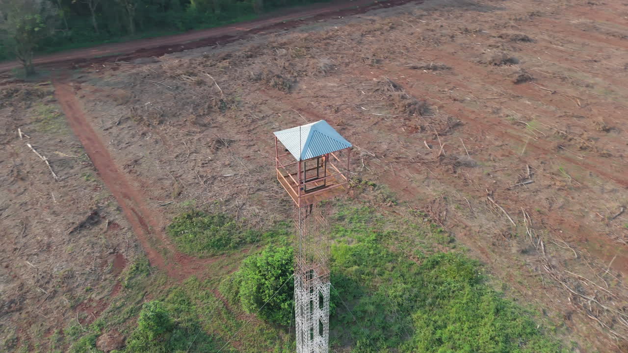Aerial view of a deforested area with a forest guard tower in a reforestation field.
